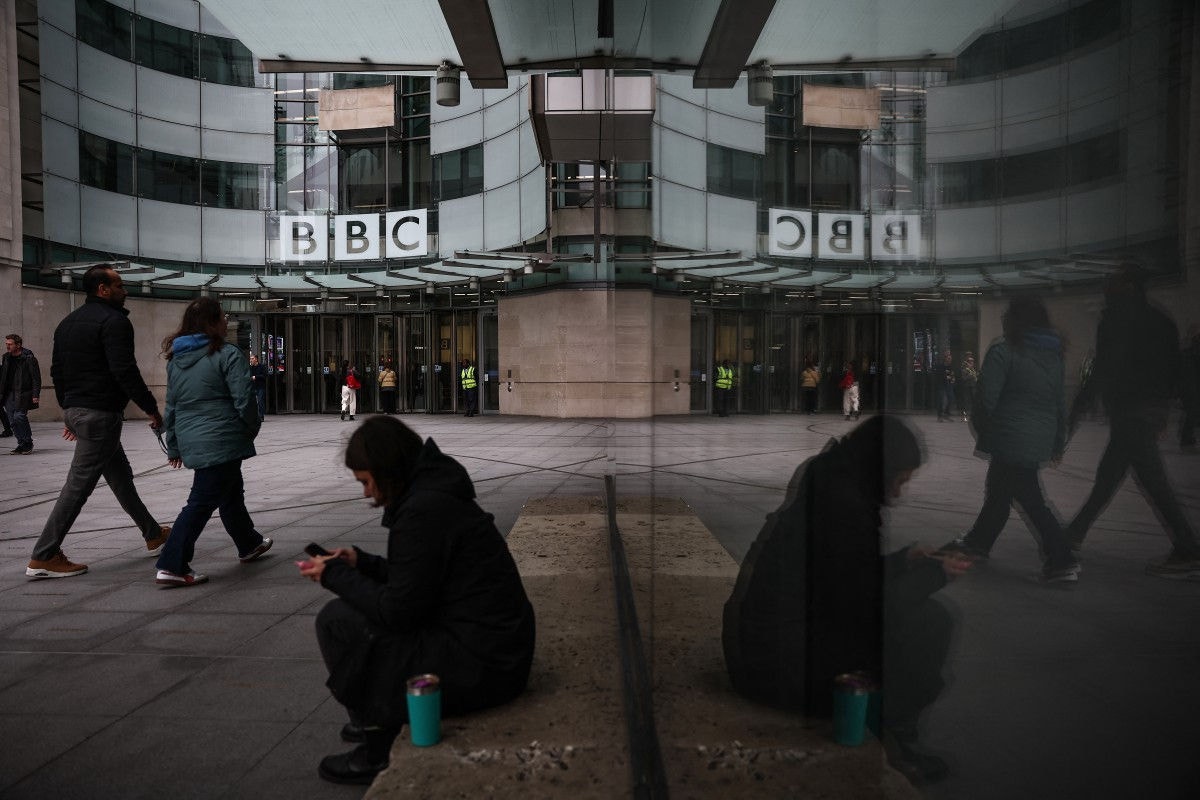 Pessoas caminham em frente à entrada dos escritórios da BBC em Londres, em 11 de novembro de 2025. (Photo by HENRY NICHOLLS / AFP)