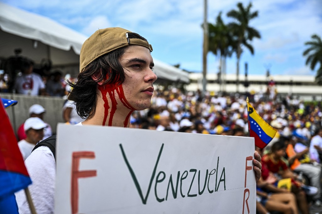 A demonstrator holds a sign as they take part in the "Protest for Truth" rally called by the Venezuelan opposition to demand that the Venezuelan government recognize Edmundo Gonzalez Urrutia's victory in the presidential elections, in Miami, Florida, August 17, 2024. Venezuelan opposition leader Maria Corina Machado urged supporters August 16, 2024, to "keep up the fight" on the eve of protests called against the election victory claimed by strongman Nicolas Maduro but widely rejected at home and abroad. Machado had called for fresh demonstrations in more than 300 cities in Venezuela and abroad, what she called a "Protest for the Truth." (Photo by CHANDAN KHANNA / AFP)